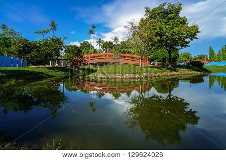 Landscape of tropical lake with bridge and reflection of water over sunny day at Damai garden,Labuan,Malaysia.