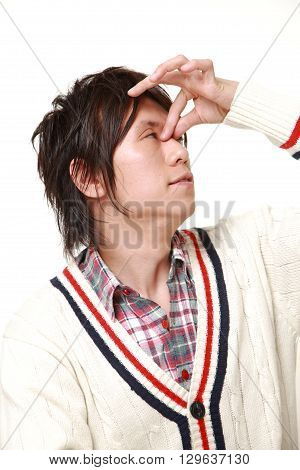 portrait of young Japanese man suffers from Asthenopia on white background