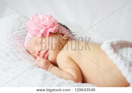 A sleeping baby girl in a pink headband