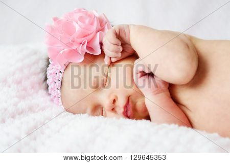 A sleeping baby girl in a pink headband