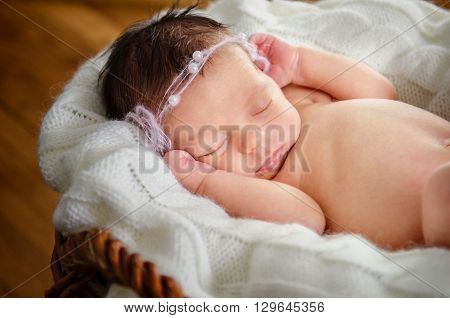 A baby girl in is sleeping in a basket