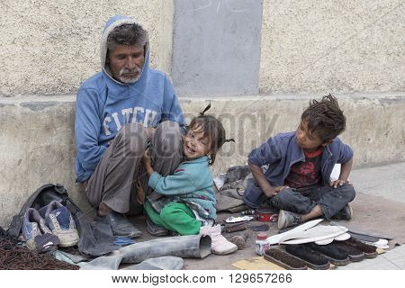 LEH INDIA - SEPTEMBER 08 2014: An unidentified beggar family begs for money from a passerby in Leh. Poverty is a major issue in India