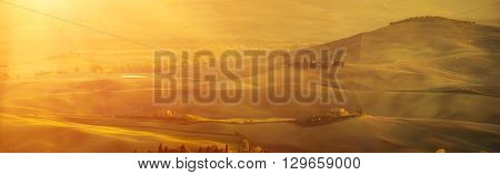 Wavy fields in Tuscany at sunet, Italy. Natural outdoor seasonal autumn background with sun shining. Panoramic view.