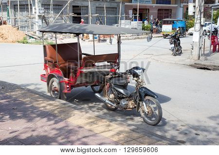 KAMPOT, CAMPBODIA - 21 NOVEMBER 2011: Cambodian red tuk-tuk parked on the city street on 21st of November 2015 in Kampot, Cambodia. Tuk-Tuk is the most popular transport in Cambodia