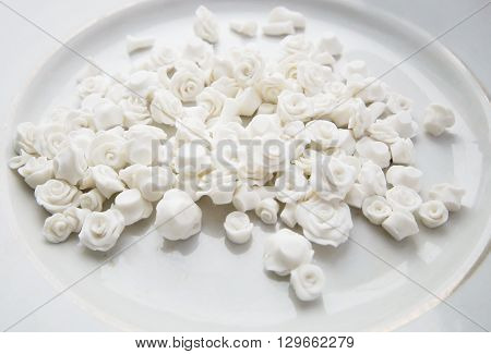 a lot of small white roses handmade from polymer clay