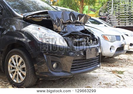 A wrecked car lays in wait after a vicious car accident. Rescue workers linger in the background.