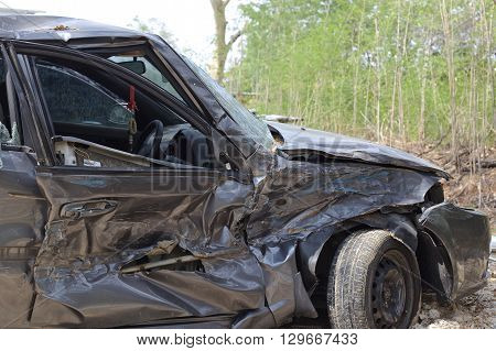 A wrecked car lays in wait after a vicious car accident. Rescue workers linger in the background.