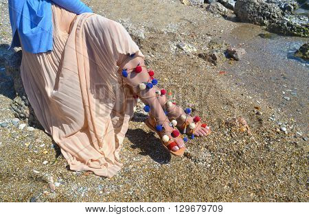 woman advertises traditional greek sandals gladiator on beach