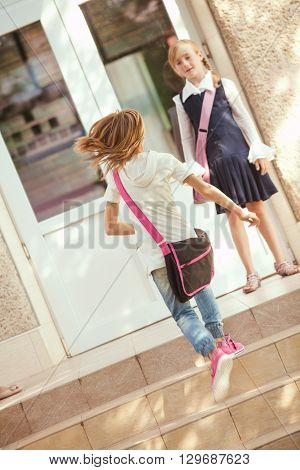 Two schoolgirls outdoors near the door of school building
