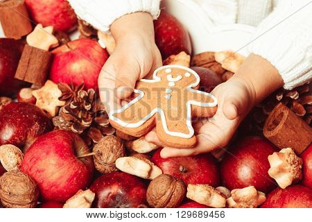 Child's hands hold a red apple and gingerman cookie