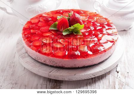 Strawberry cake on white wooden plate with mint leaf