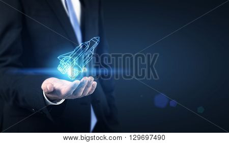Start up concept with businessman holding abstract digital rocket