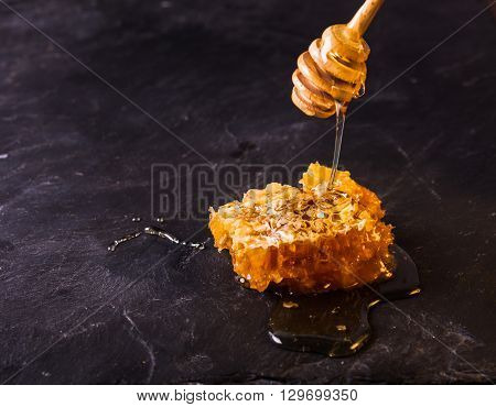 Honey drip and comb over black slate background