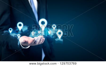 Businessman holding map with location pins on dark background. Traveling concept