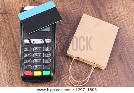 Credit card reader payment terminal with contactless credit card and paper shopping bag cashless paying for shopping finance concept