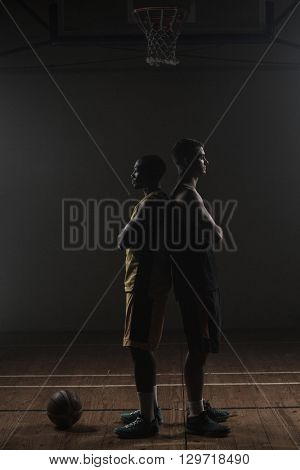 Basketball players posing back to back on a gym