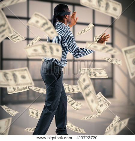 Blindfolded businessman with arms out against room with large window showing city