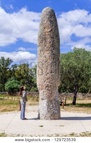 Castelo de Vide, Portugal - April 26, 2015: Woman looking at the Standing Stone / Menhir of Meada, the largest of the Iberian Peninsula. A mysterious phallic prehistoric fertility monument.