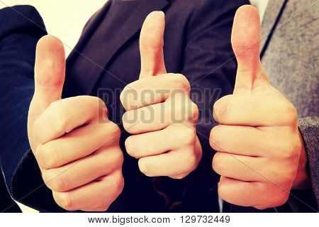 Three business people showing thumbs up