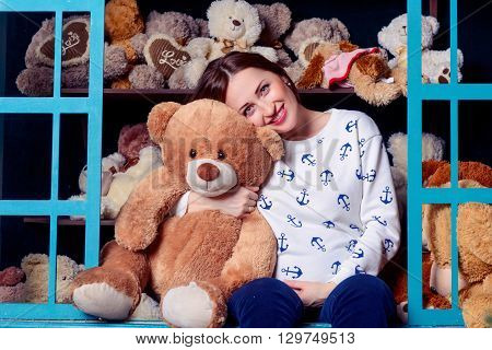 The pregnant woman hugging a teddy bear on the background of children's toys