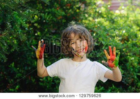 Child himself dirty in the paint and show his dirty hands into the camera. Cild has fun and painting and drawing. Children's creativity. Art for baby. Emotions. Delight.