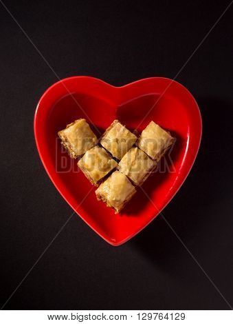 Popular middle eastern dessert - Paklawa in a red heart shaped dish. Unhealthy food concept.