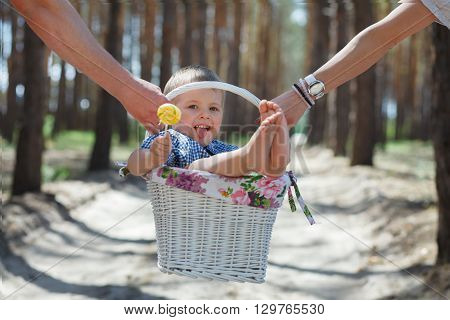 Happy family with child in backet walking at bright summer day