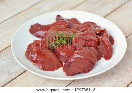 Raw Liver On The White Plate On The Wooden Background