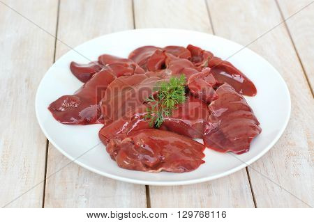 Raw Liver On The White Plate On The Wooden Background