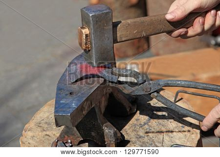 Forging steel billet on the anvil with a hammer