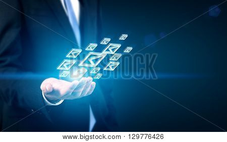 Businessman with email icons in hand on dark background