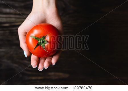 tomato in hand on a wooden background