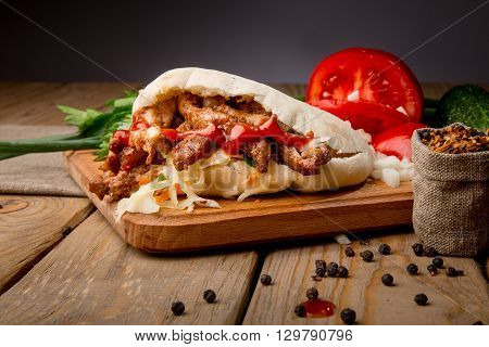 Tasty pita with fresh salad on wooden table