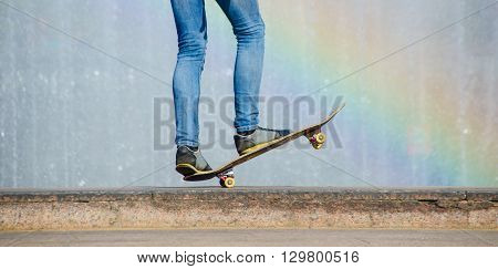 Balance on a Skateboard with raindow background. Man making skateboard trick in a city in sunny day near fontain.