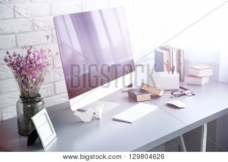 Modern interior. Comfortable workplace. Wooden table with beautiful bouquet of flowers and computer on it.