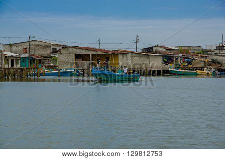 Muisne, Ecuador - March 16, 2016: Muisne town as seen from water, modest wooden houses sitting on poles waterfront pacific ocean, city buildings background and beautiful blue sky.
