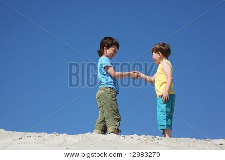 Two boys greet on sand