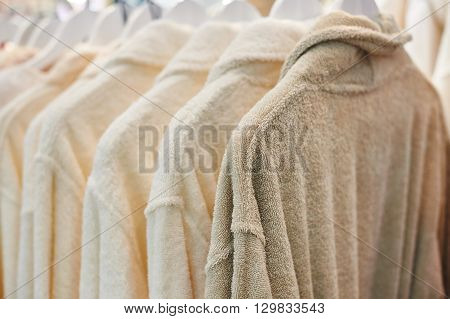 many white bathrobes hanging in wooden closet.