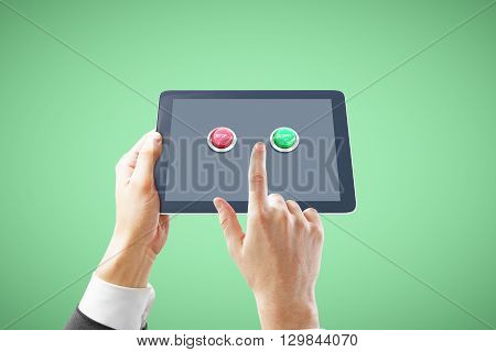 Businessman hands holding tablet with stop and start buttons on green background. 3D Rendering