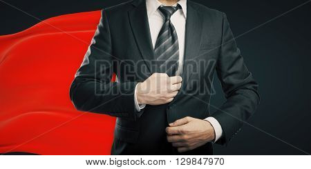 Businessman with red superhero cape on dark background
