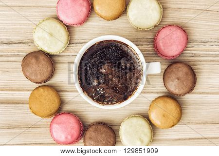 Cup of black coffee with tasty french colorful macarons in the circle shape. Sweet delight. View from above. Close up. Sweet macarons.