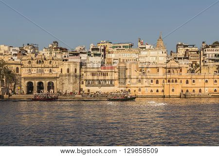 UDAIPUR INDIA - 20TH MARCH 2016: A view of part of the City of Udaipur at the lake waterfront during the day close to sunset. People and boats can be seen.