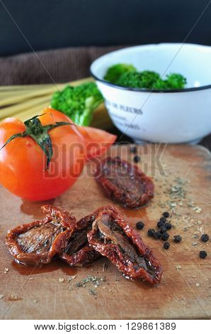 Dried tomato and spice on wooden cutting board