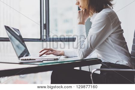 Working Process in Modern Office. Young Woman Account Manager Working at Wood Table with New Business Project. Typing keyboard, Using Contemporary Laptop. Horizontal. Film effect. Blurred background.