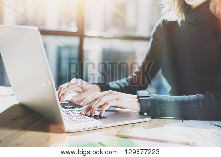 Work Process in Modern Office. Young Account Manager Working at Wood Table with New Business Project.Typing Contemporary Laptop keyboard, Wearing Smartwatch. Horizontal. Film effect.Blurred background.