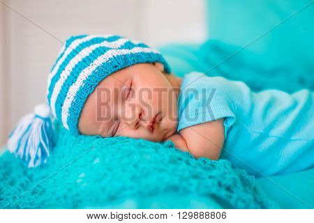 The baby sleeps on the tummy in a striped cap with a pompon