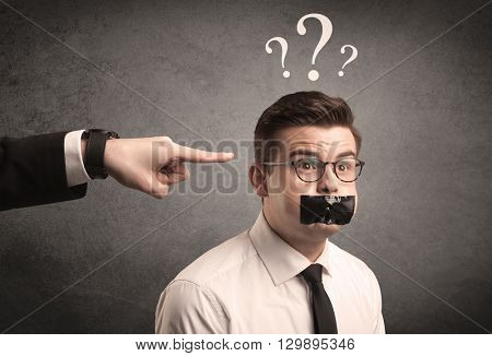 Caucasian business hand pointing at scared employee with big white question marks above his head