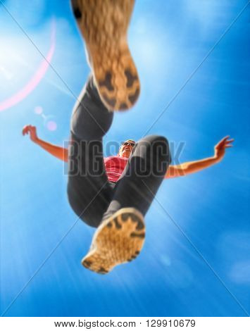 a woman dressed in active wear jumping over the camera with a wide angle lens during summer time with a lens flare in the corner toned with a vintage retro hdr instagram filter effect app or action