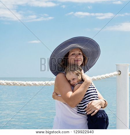 A pregnant young mother with a small daughter (3 years old) on the beach. Selective focus.