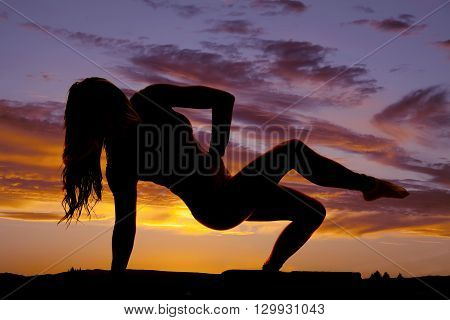 A silhouette of a woman showing off her strength and flexability with her body.